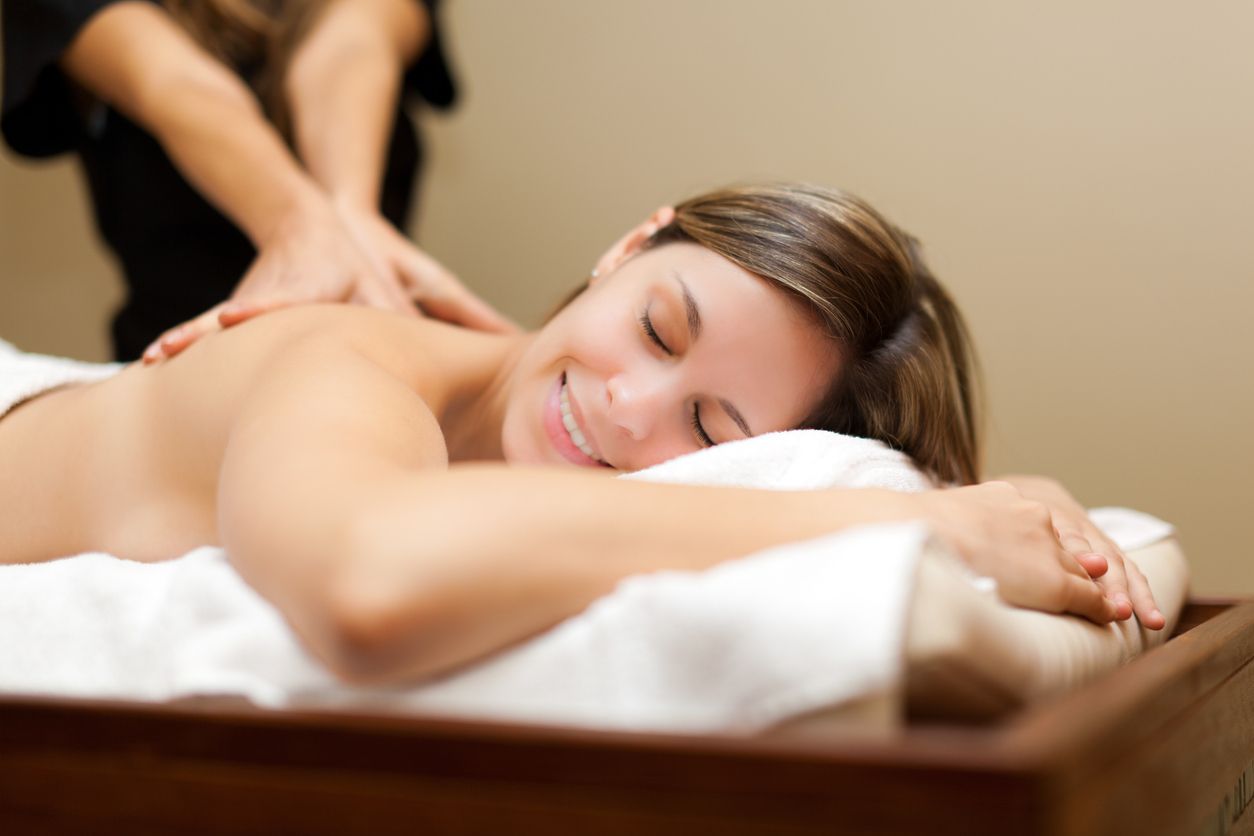 A woman is smiling while getting a massage at a spa.