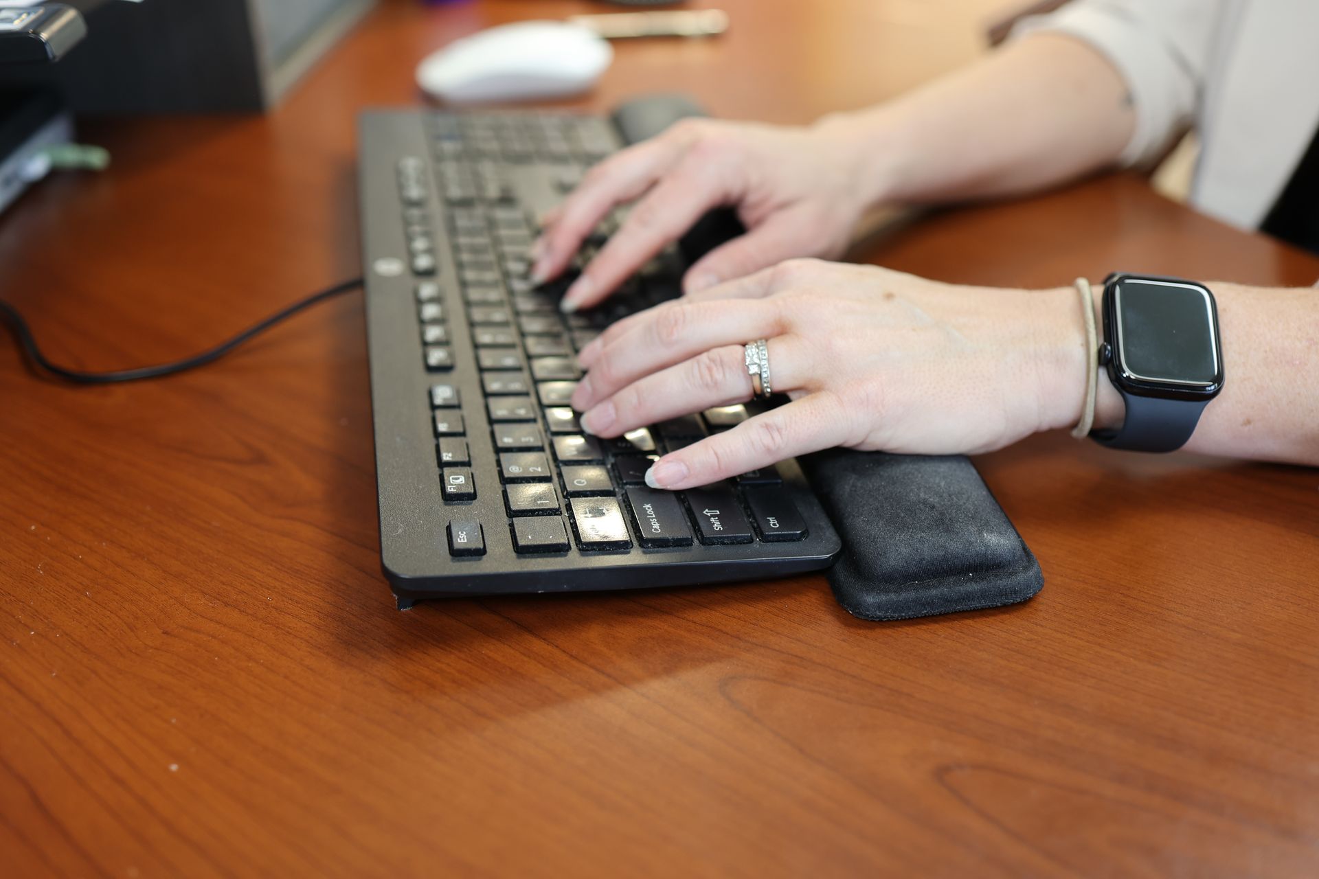 Three office workers in headsets meet around a desk with dual monitors in a bright office.