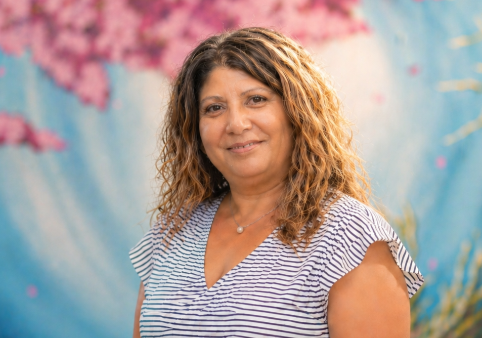 Smiling woman in a blue striped top against a pink and blue floral backdrop