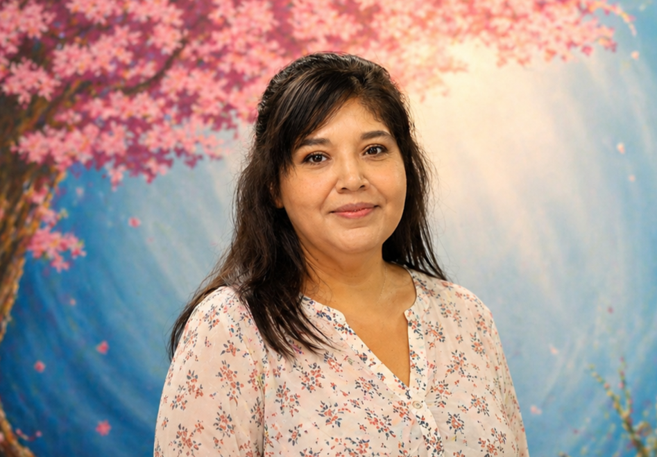 Portrait of a woman in a floral blouse against a pink blossom and blue background