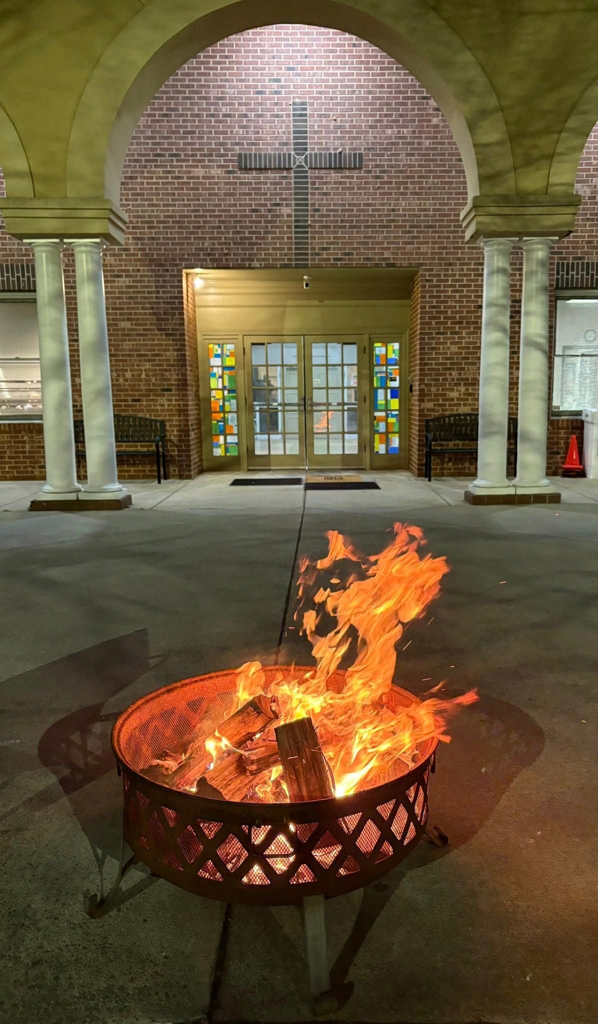 Lit fire pit in a covered brick archway outside a building entrance at night