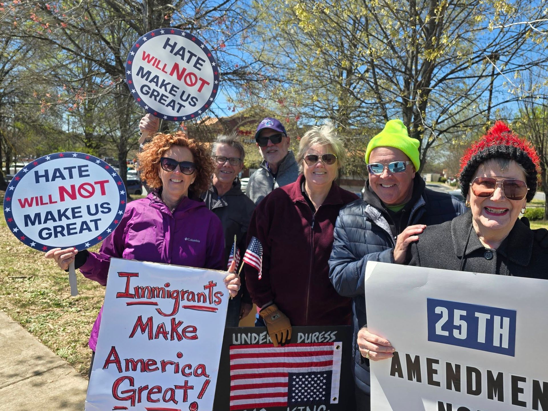 Protesters holding signs against hate and for the 25th Amendment outdoors in winter attire