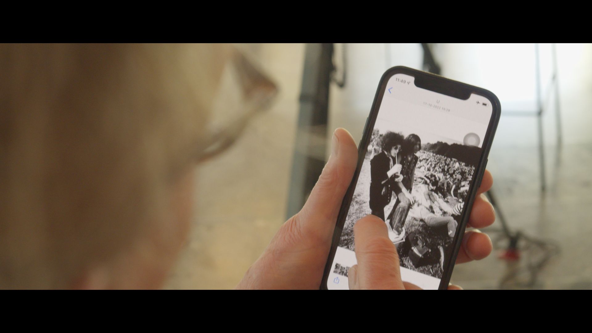 Person holding a smartphone showing a black-and-white crowd photo on the screen