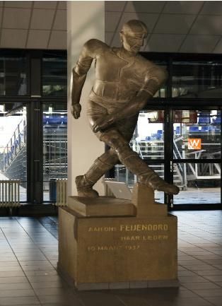 Bronze hockey statue on a pedestal in a stadium concourse