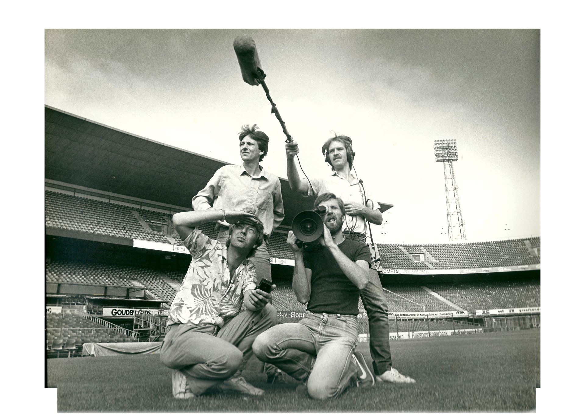 Three people celebrating on a baseball field, posing with trophies in a stadium.