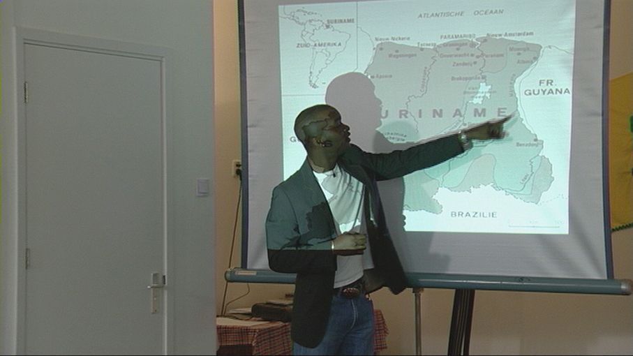 Person pointing at a projected map during a presentation in a classroom.