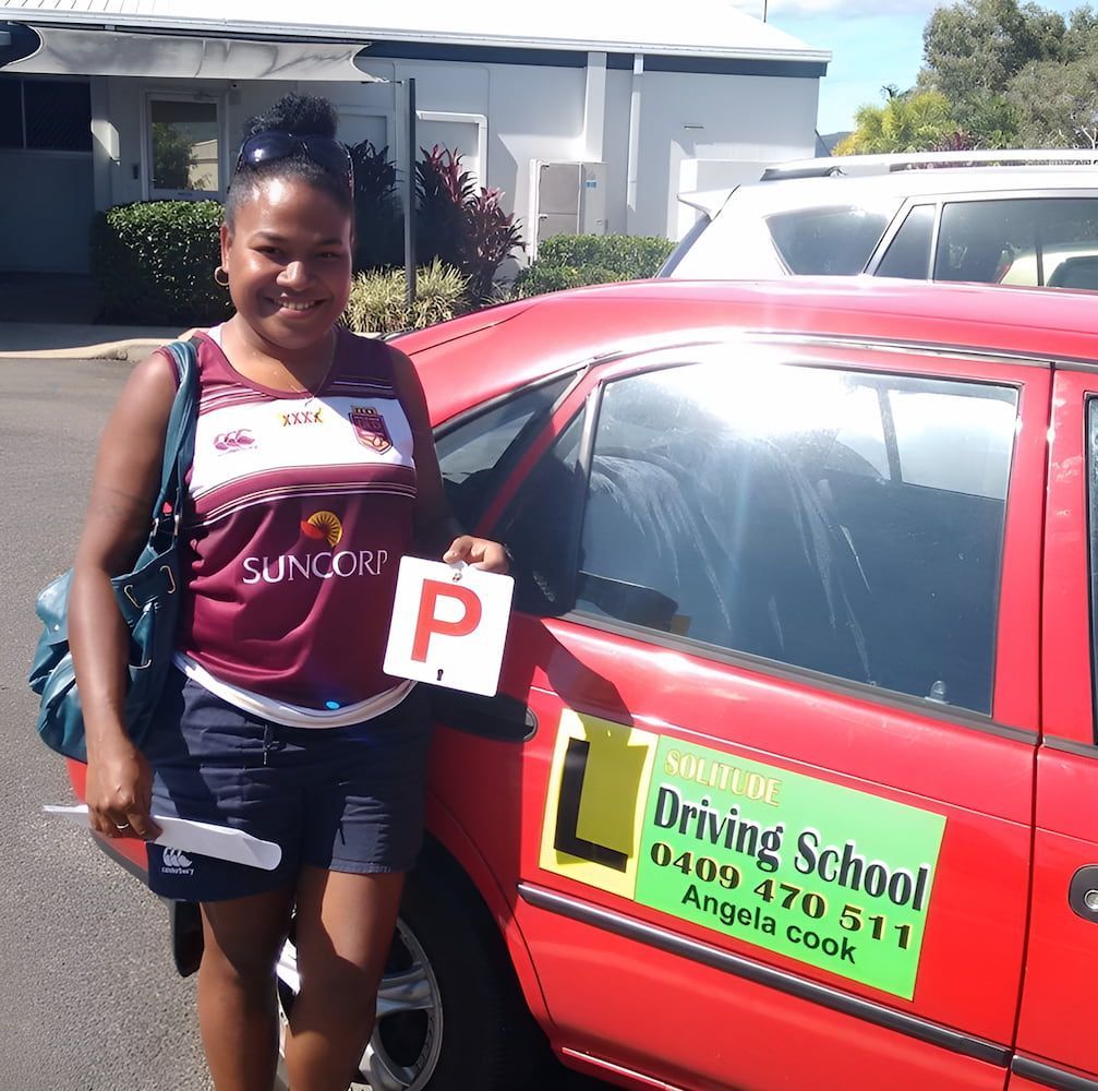 A Woman Standing Next To A Red Car That Says Driving School — Solitude Driving School In Mooroobool, QLD