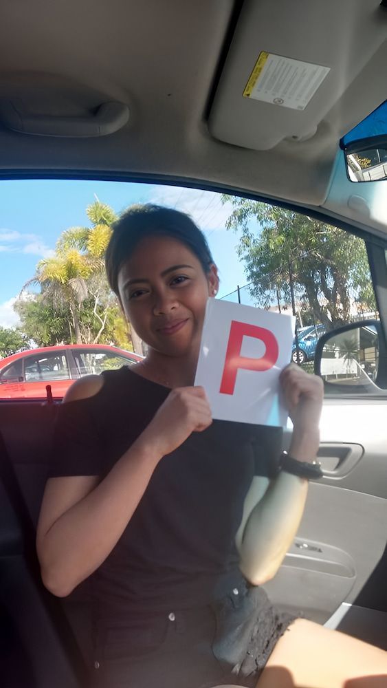 A Woman Is Sitting In A Car Holding A P Plate — Solitude Driving School In Mooroobool, QLD