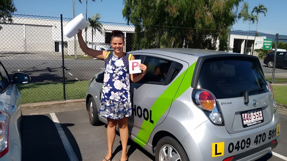 A Woman Is Standing In Front Of A Car That Says L On The Back — Solitude Driving School In Mooroobool, QLD