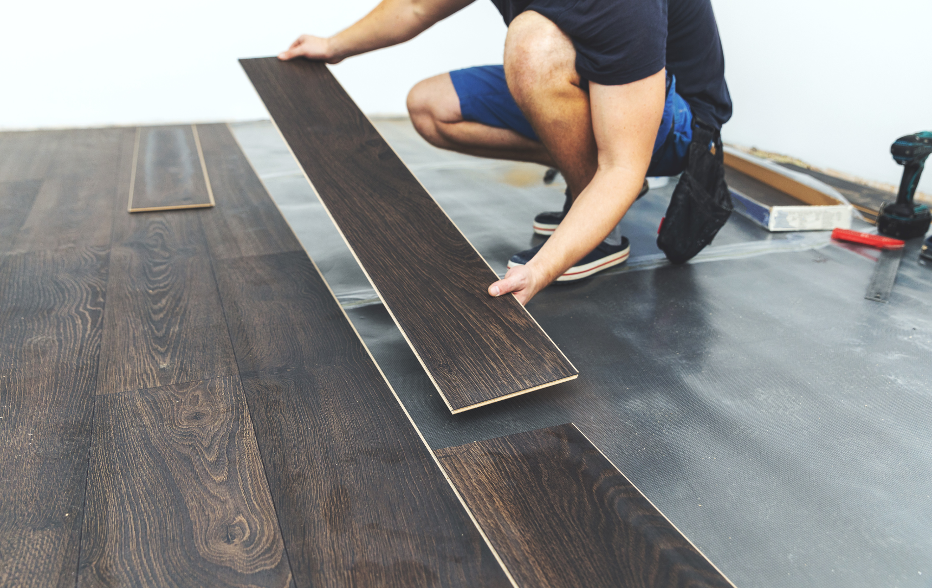 A man is installing a wooden floor in a room.