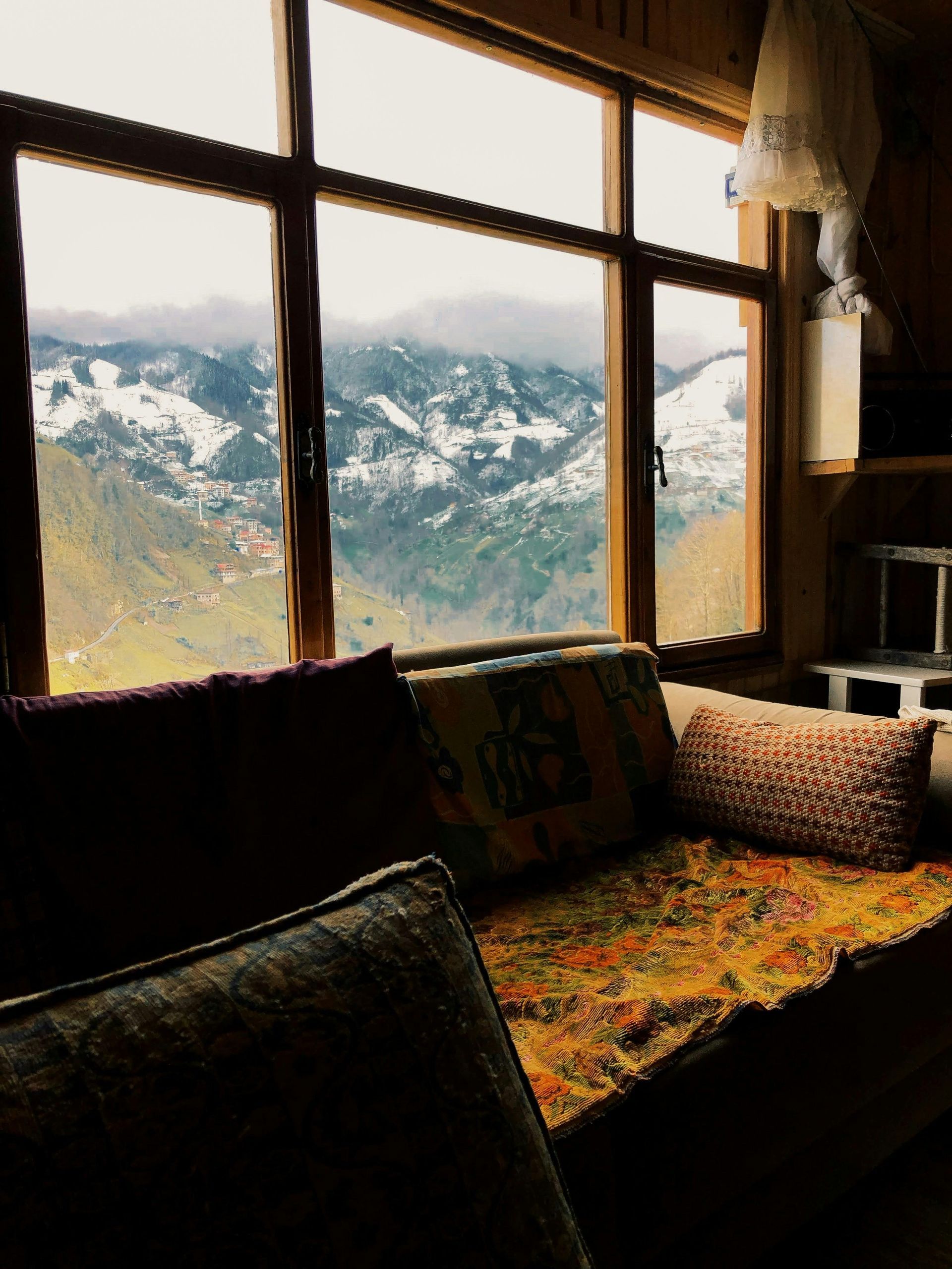 A cozy couch with brown cushions in front of a window with a view of the mountains, and gentle sunlight, representing retreat