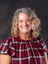 A woman in a plaid shirt is smiling for the camera.