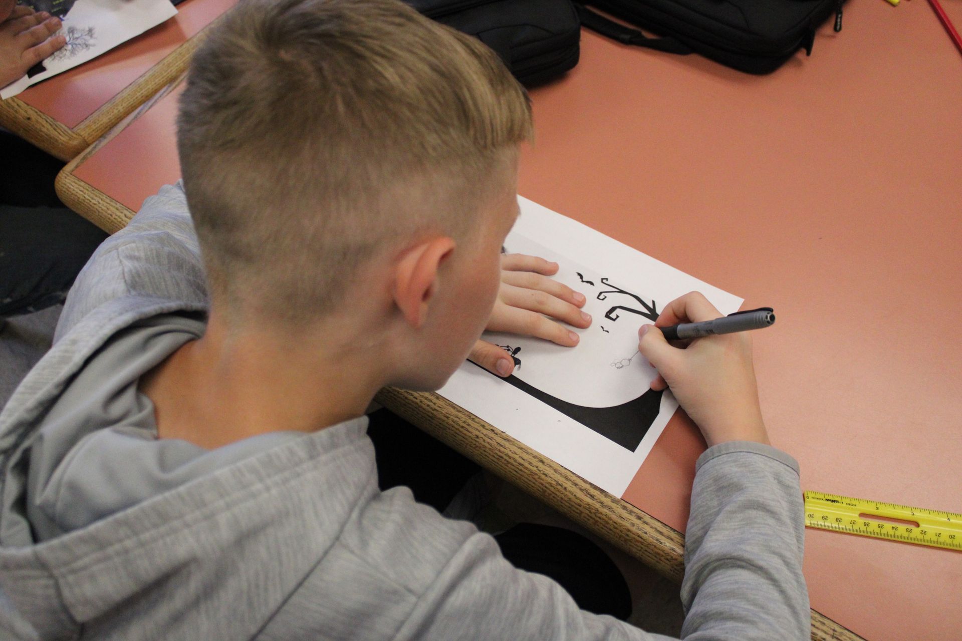 A boy is writing on a piece of paper with a pen