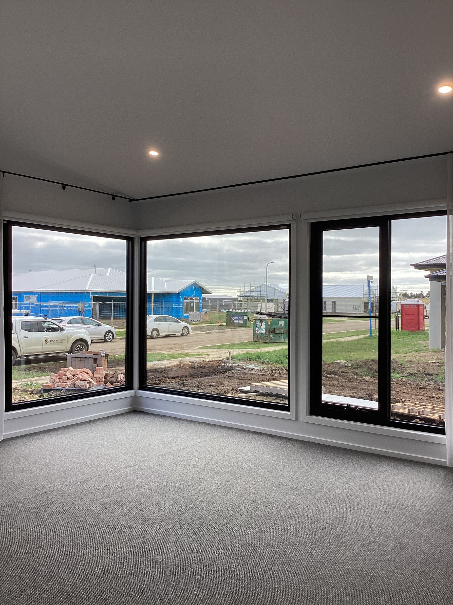 Empty modern room with large corner windows overlooking a construction site — Twomey Homes in Delacombe, VIC