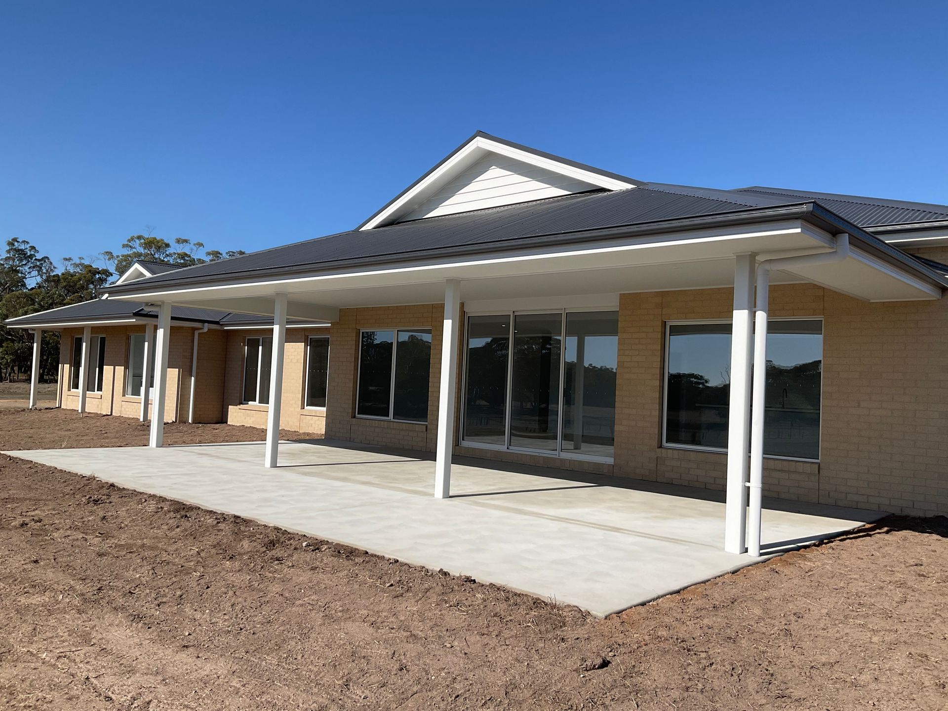 Single-story brick house with a covered porch and white columns under a blue sky — Twomey Homes in Delacombe, VIC