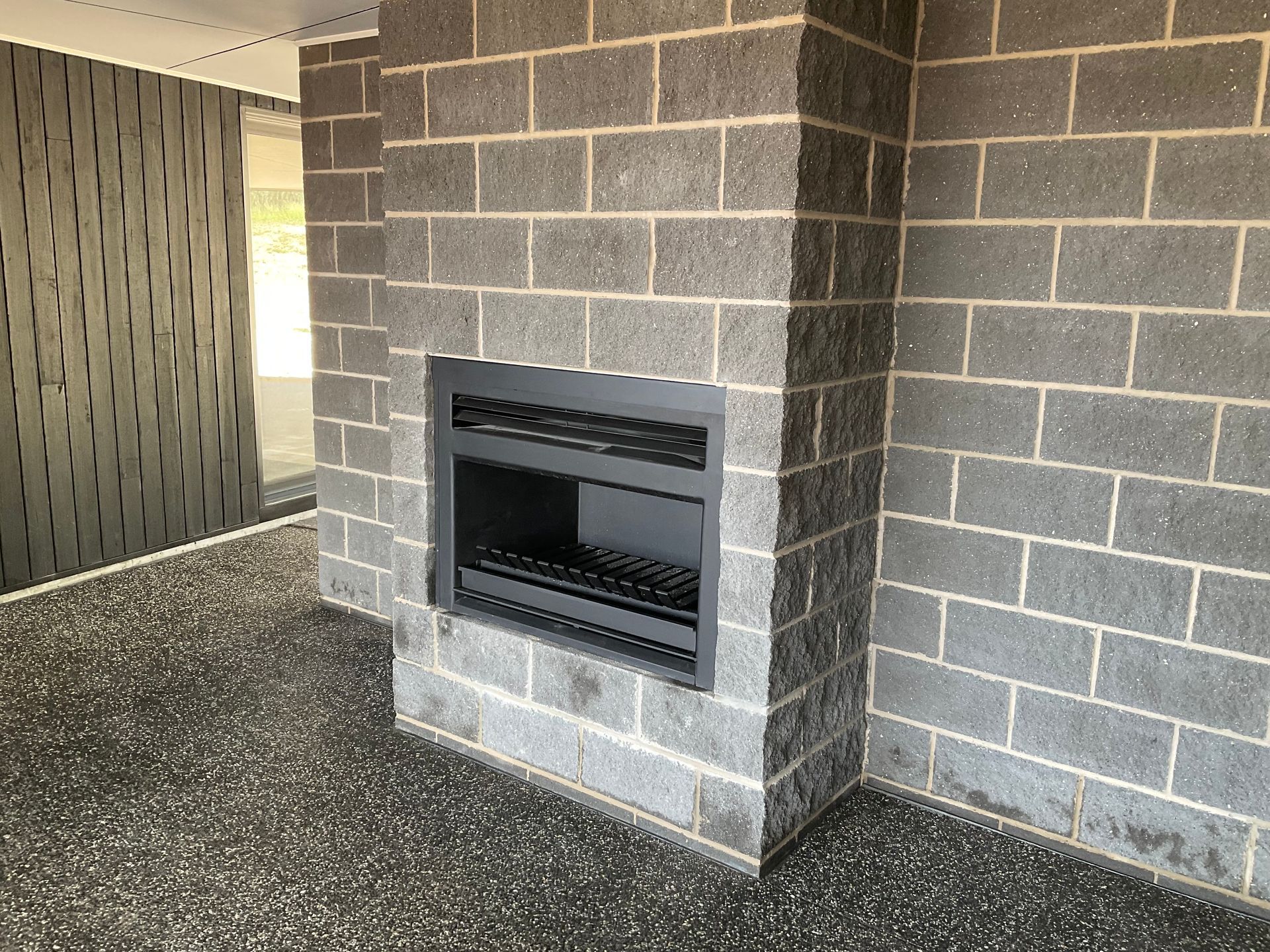 Concrete fireplace set into a grey brick wall in an unfinished indoor space — Twomey Homes in Delacombe, VIC