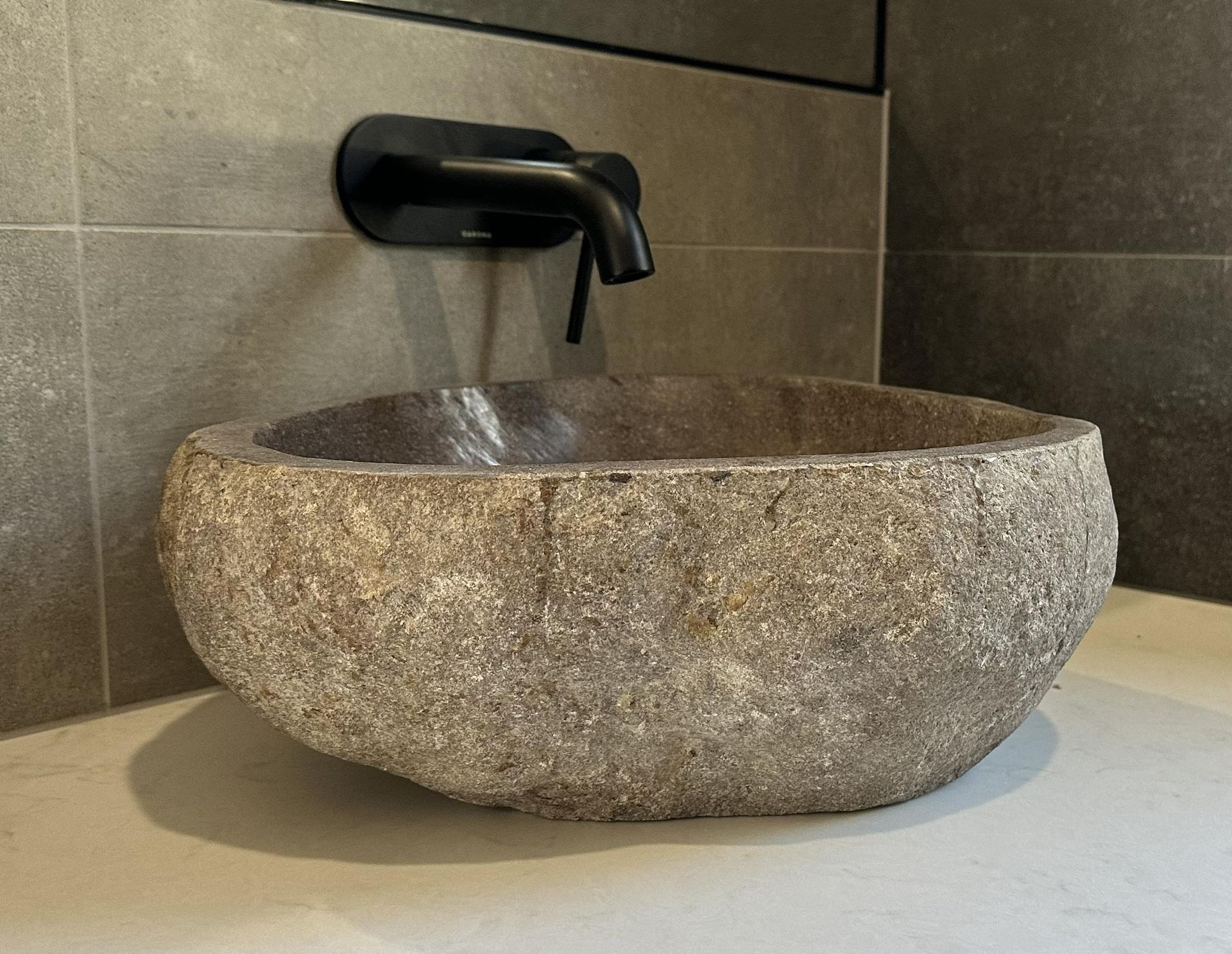 Rustic stone vessel sink beneath a matte black wall-mounted tap in a tiled bathroom — Twomey Homes in Delacombe, VIC