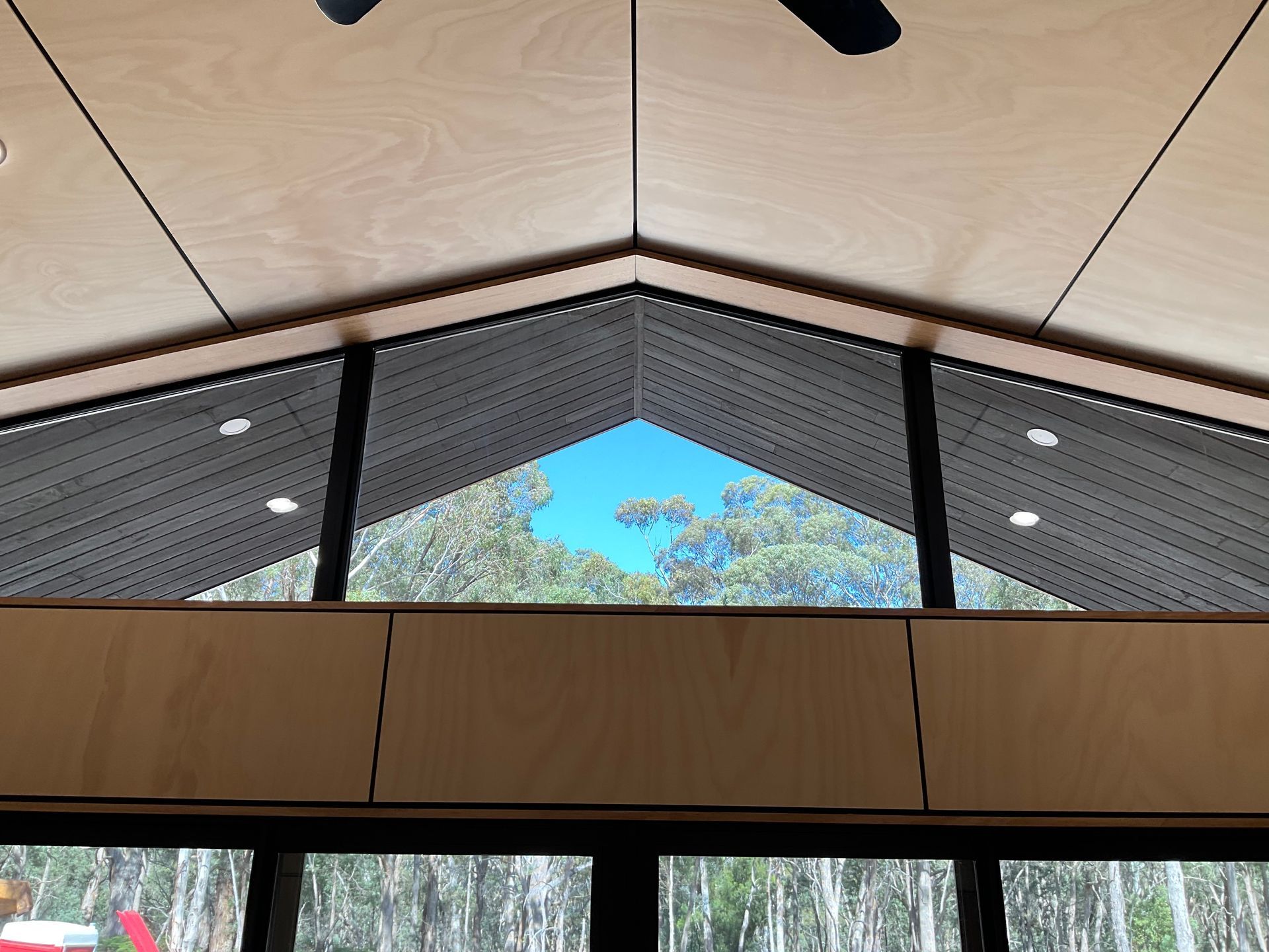 Modern interior ceiling with wood panels and skylight framing blue sky and trees — Twomey Homes in Delacombe, VIC