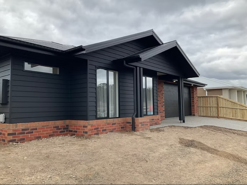 Modern black brick house exterior with covered porch under cloudy sky — Twomey Homes in Delacombe, VIC