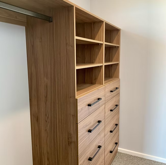 Wooden closet organizer with open shelves and multiple drawers in a carpeted room — Twomey Homes in Delacombe, VIC