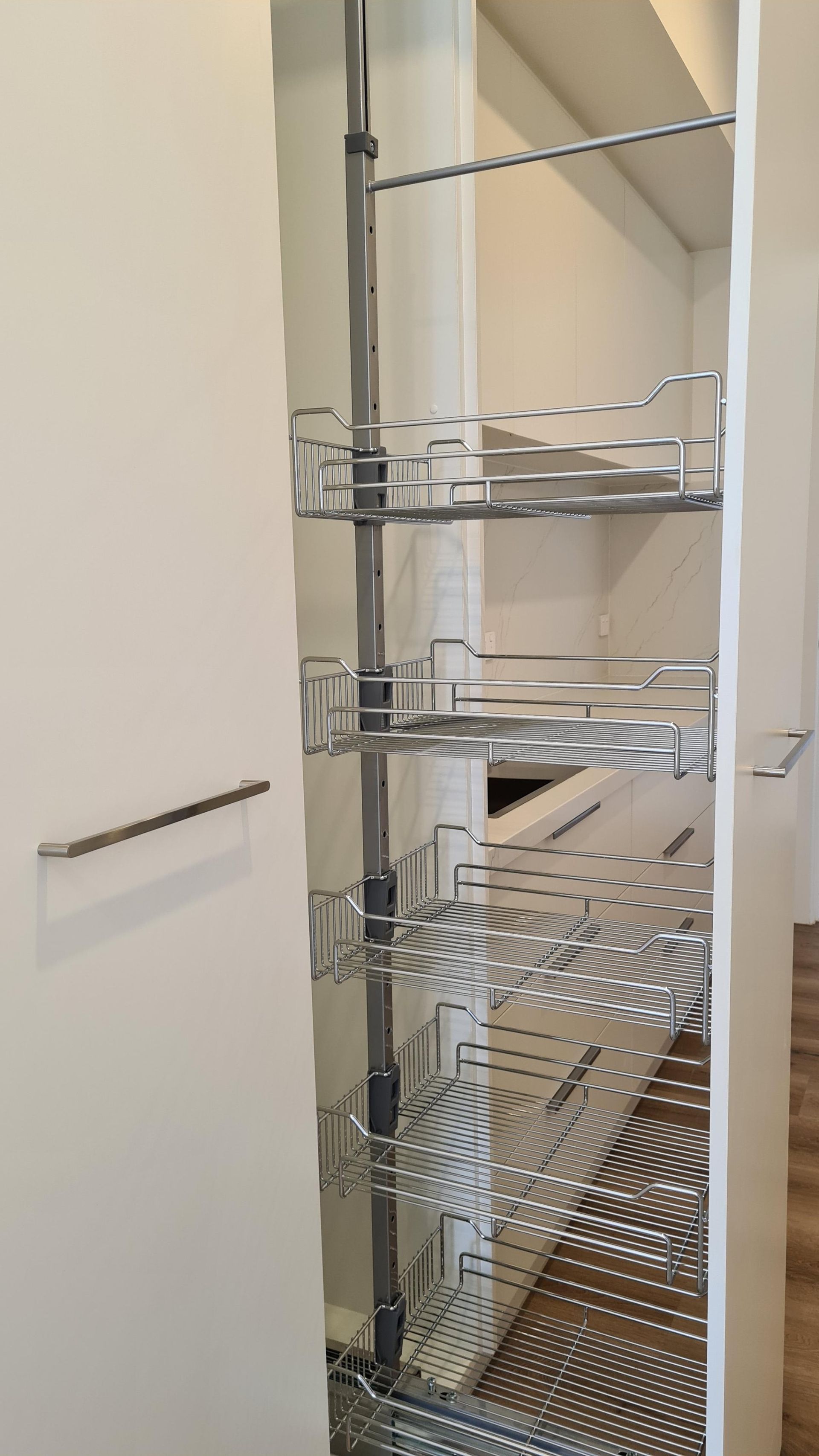 Pull-out wire pantry shelves inside a narrow closet, mostly empty — Twomey Homes in Delacombe, VIC
