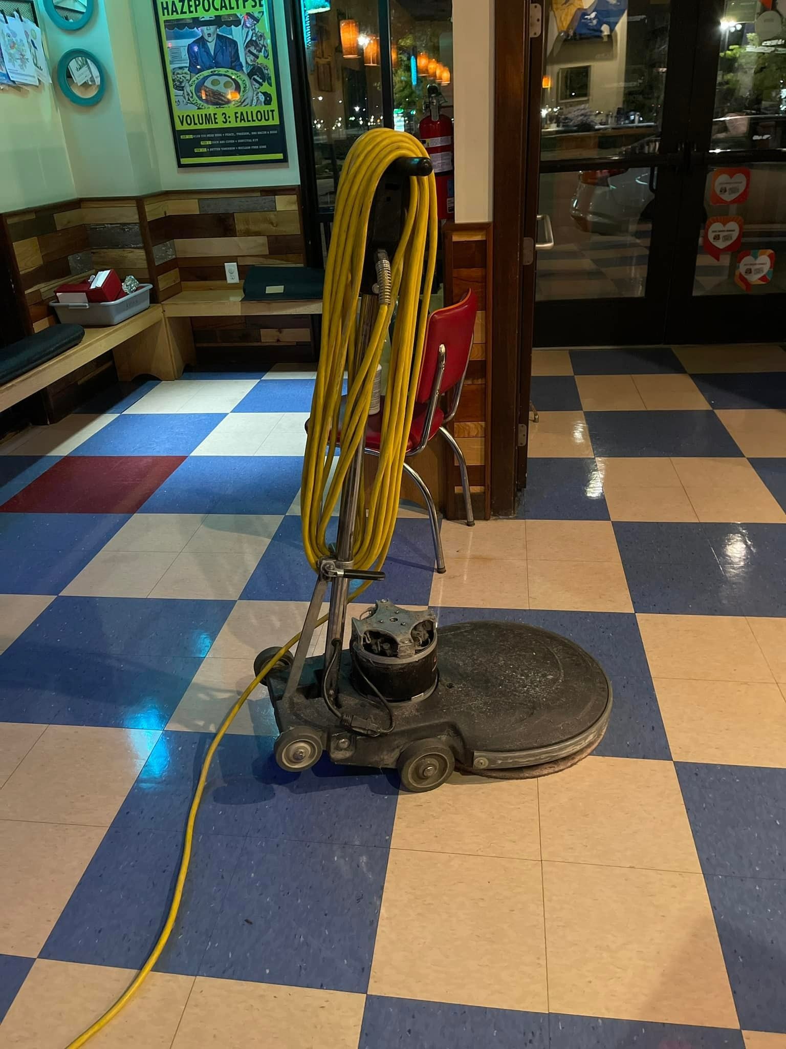 Floor buffer on checkered floor in a restaurant. Yellow power cord and coiled cable.