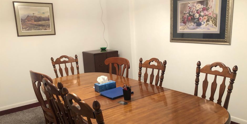 A conference room with a table and chairs and a painting on the wall.