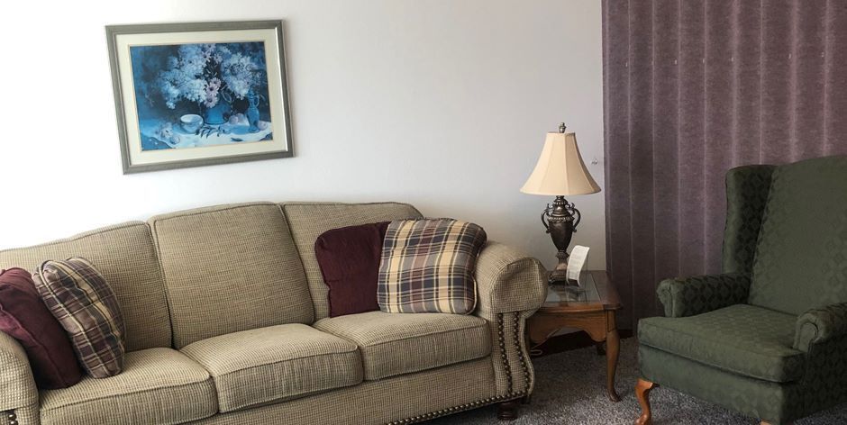 A living room with a couch , chair , table and lamp.
