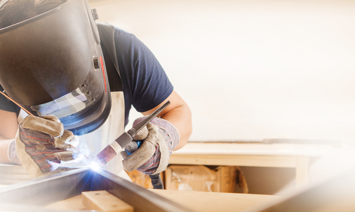 Welder in protective gear working on metal, bright sparks flying in a workshop Welder in protective gear working on metal, bright sparks flying in a workshop