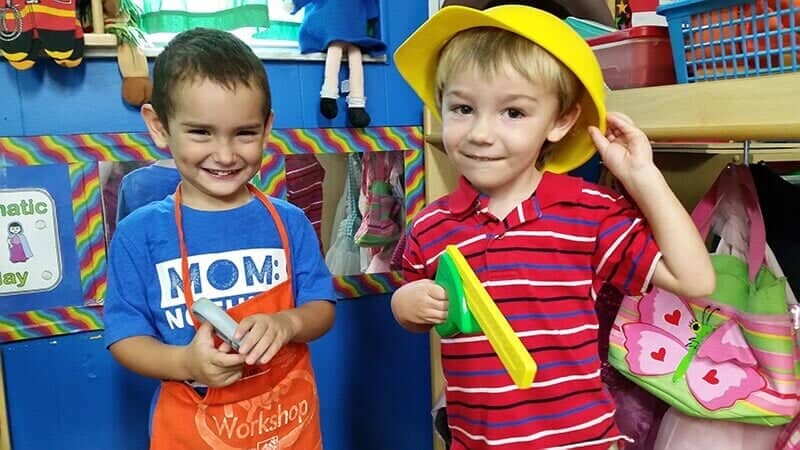 Two Boys Smiling While Holding Toys — Sarasota, FL — Shining Stars Learning Center