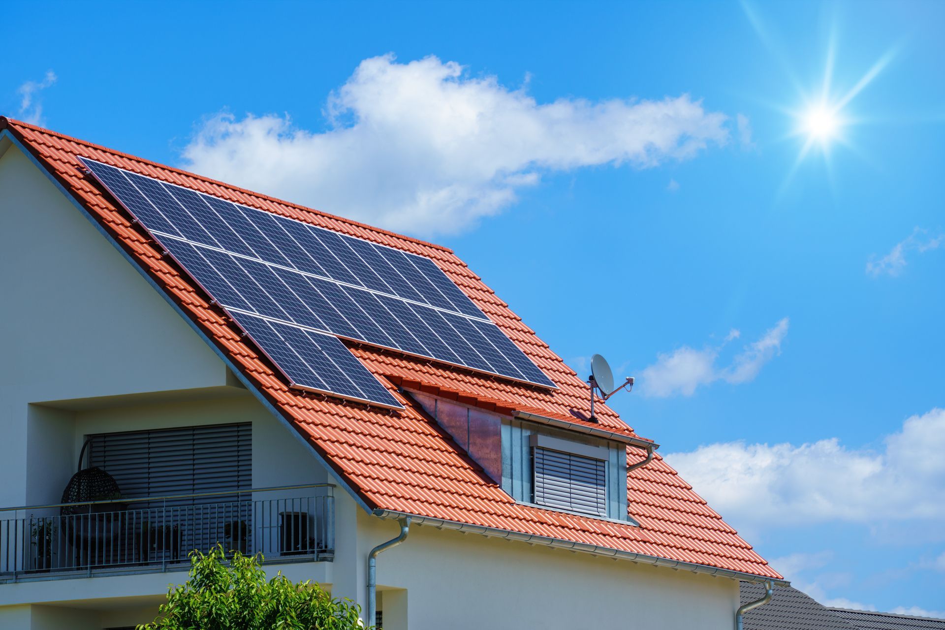 A house with solar panels on the roof and the sun shining through the clouds