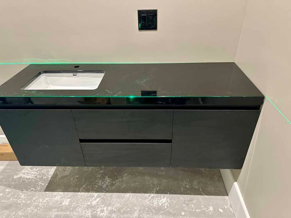 Modern black vanity with white sink in a small bathroom under construction