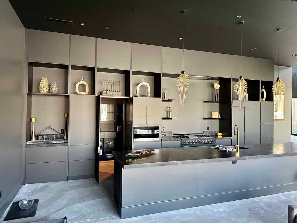 Modern minimalist kitchen with dark gray cabinetry, central island, and decorative shelves