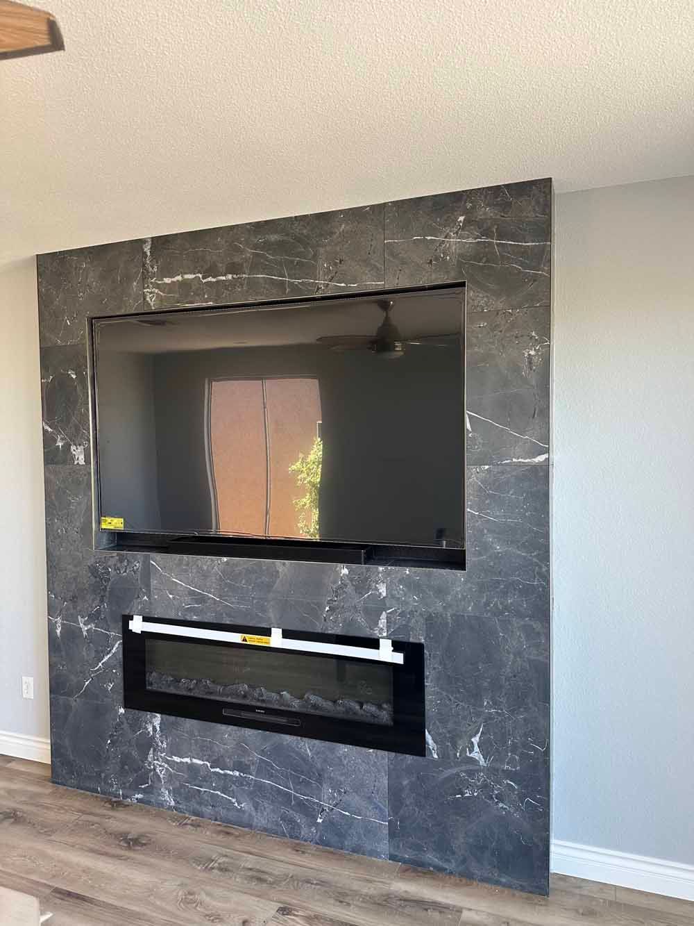 Black marble fireplace surround with a large inset opening and unfinished lower opening in a living room.