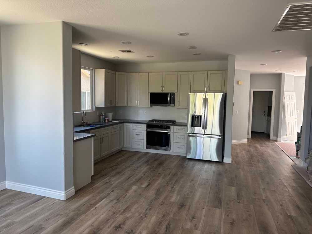 Open-plan kitchen with white cabinets, stainless appliances, and wood-look flooring