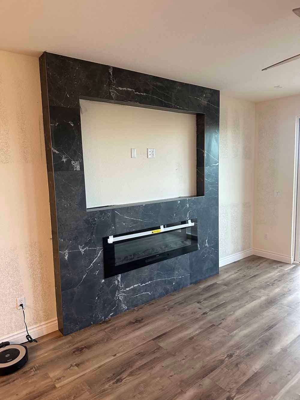 Living room with unfinished black fireplace wall and wood flooring
