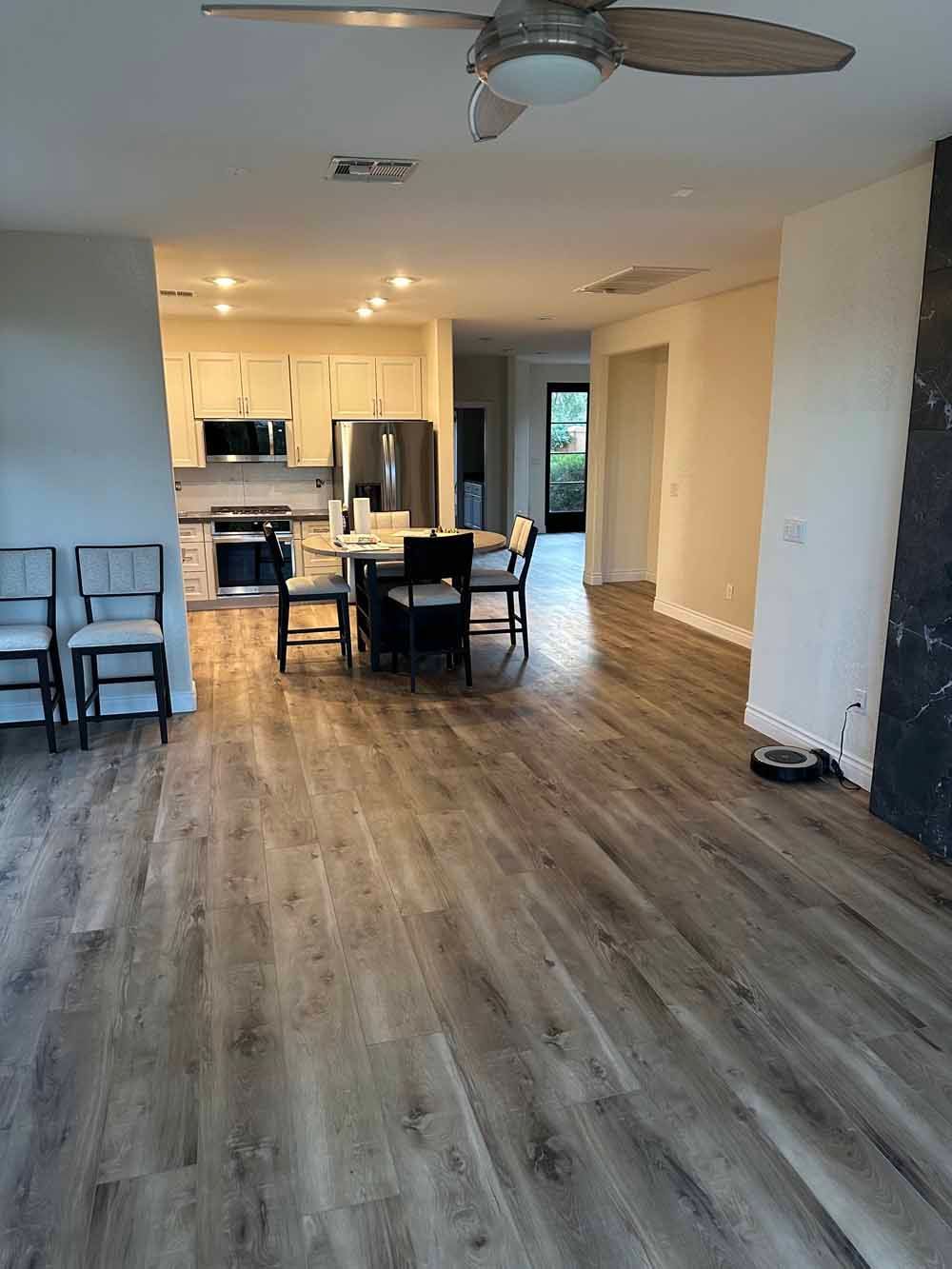 Empty open-plan living room with wood floors and kitchen area in the background