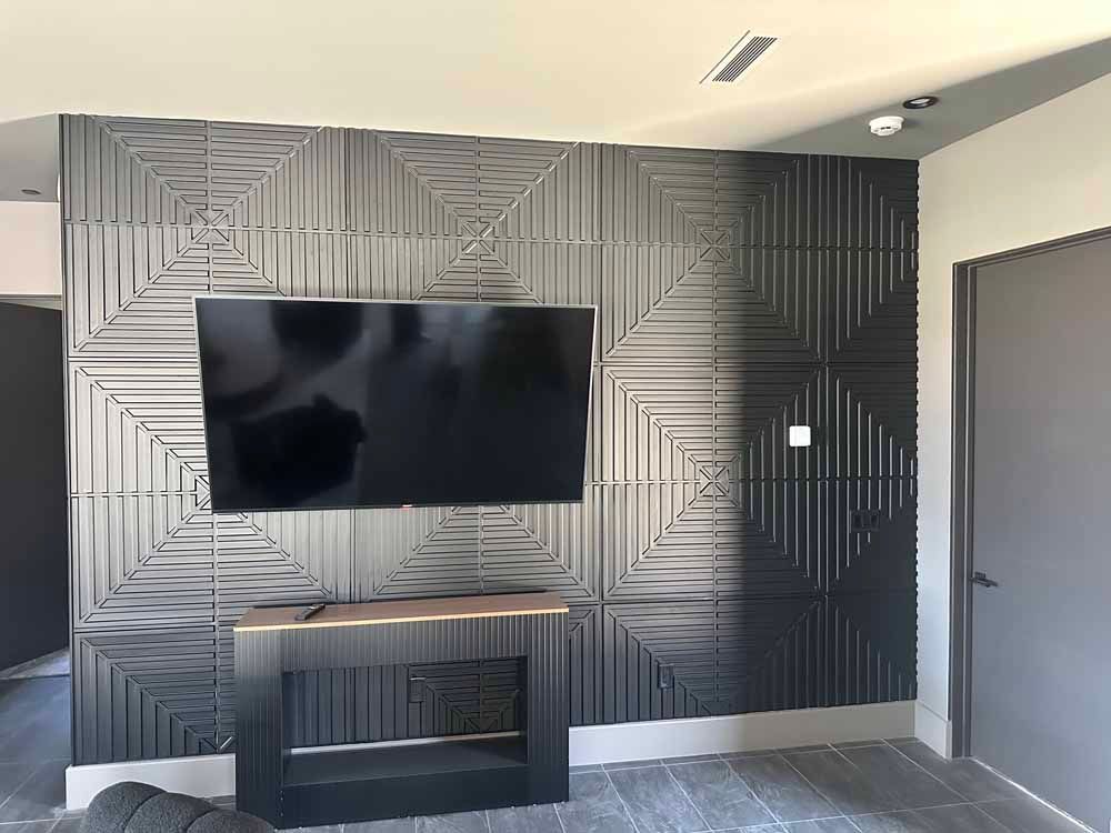 Modern room with geometric black accent wall, mounted TV, and dark fireplace console