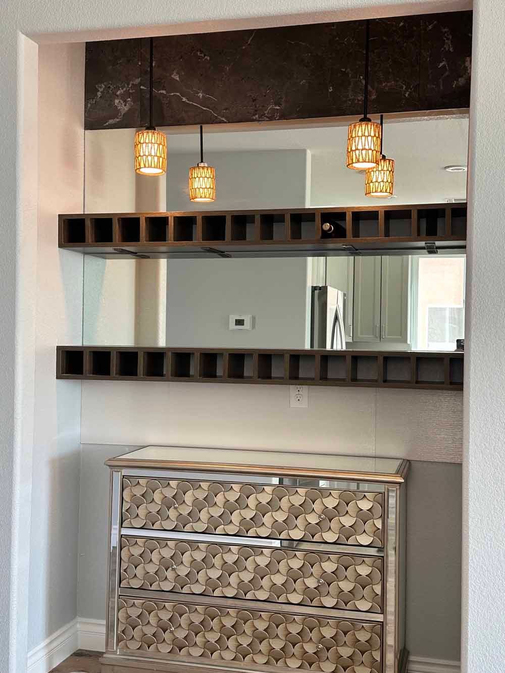 Modern interior with a decorative wall mirror, pendant lights, floating shelves, and a patterned dresser