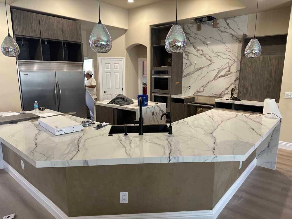 Modern kitchen with white marble island, stainless appliances, and pendant lights