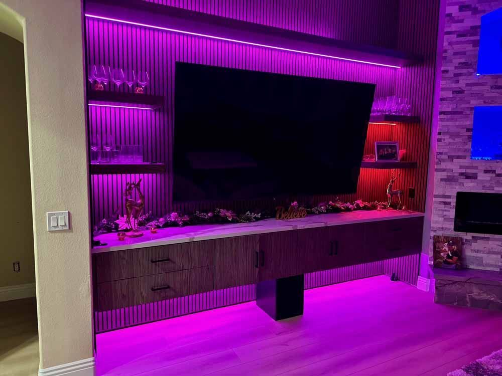 Living room TV wall with purple LED lighting, floating console, and brick accent wall
