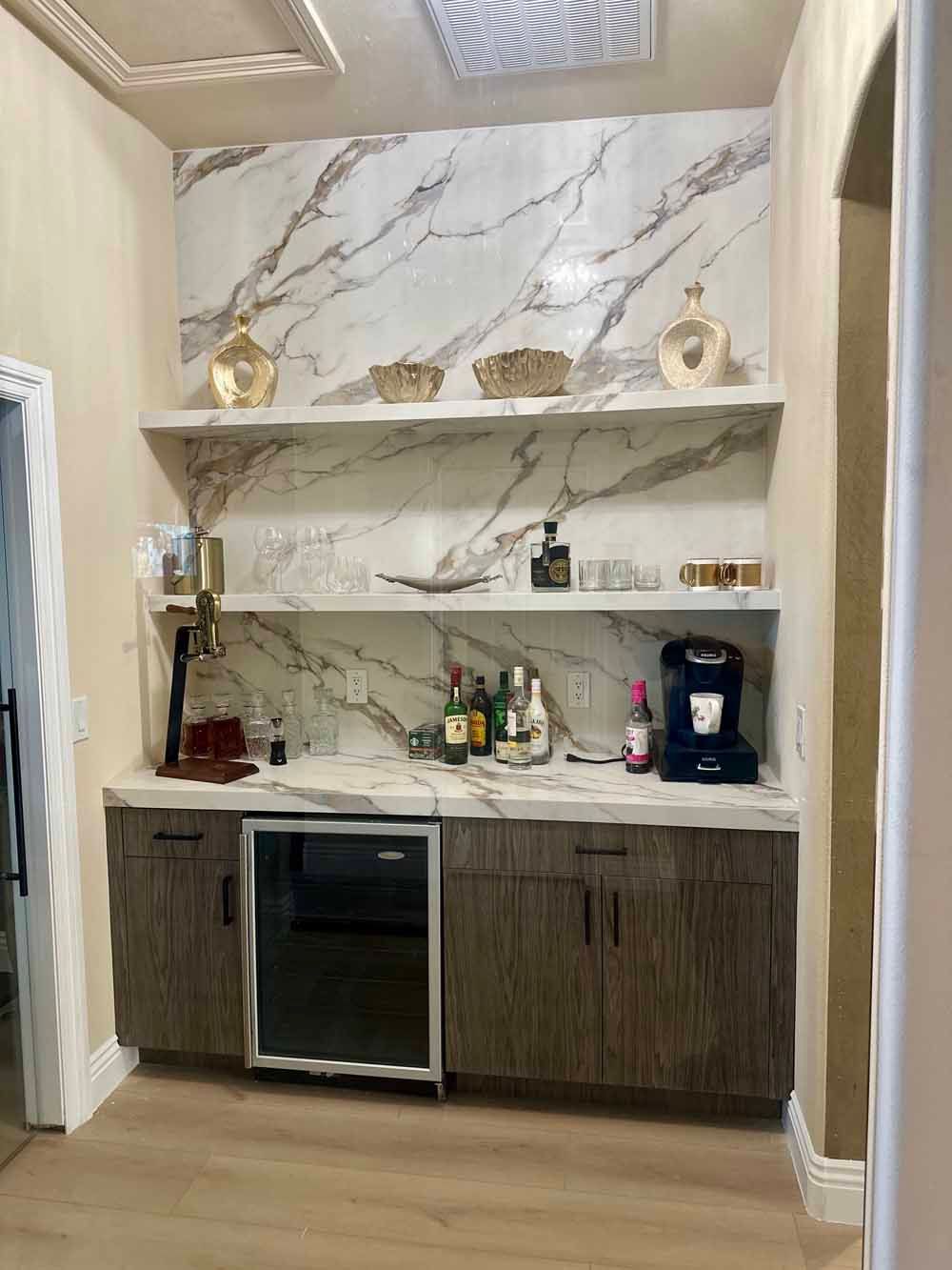 Built-in bar nook with marble backsplash, wood cabinets, shelves, and a small wine fridge