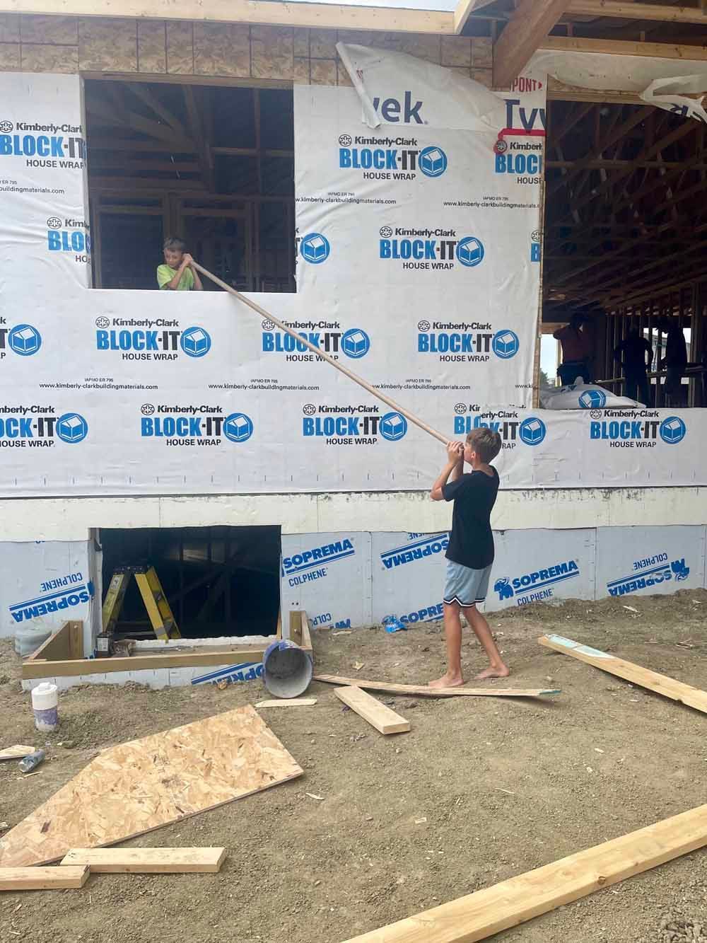 Person working on a house under construction, applying insulation panels to an exterior wall.