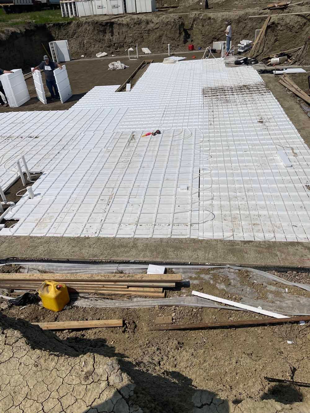 Construction site with a large white tiled slab under installation and scattered materials in the foreground