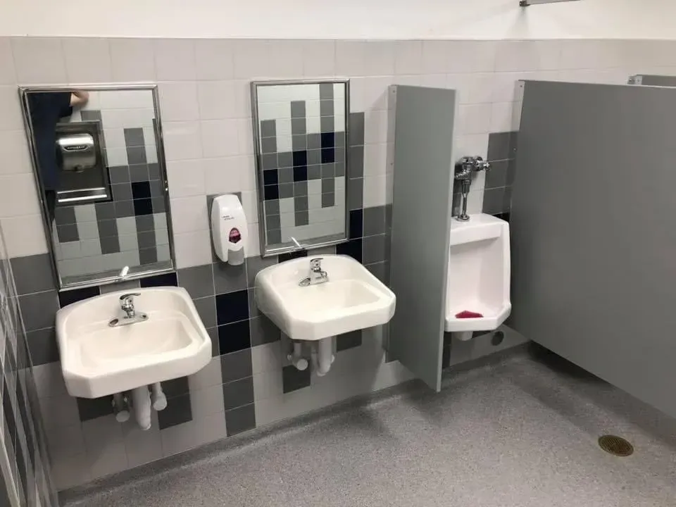 Accessible restroom with two sinks, a mirror, soap dispenser, and a private toilet stall.