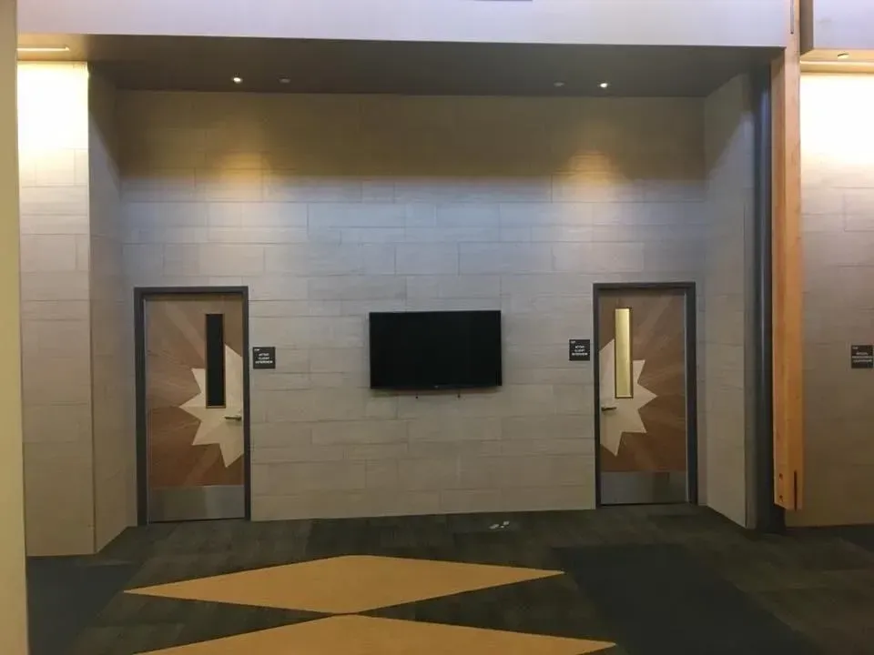 Modern lobby wall with two doors, a wall-mounted TV, and geometric floor pattern