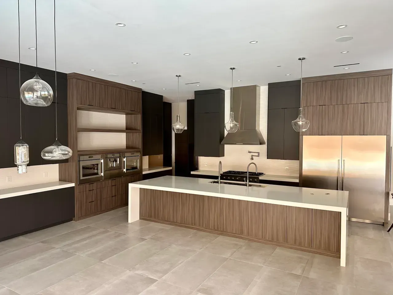 Modern kitchen with wood cabinetry, large island, stainless steel appliances, and pendant lighting