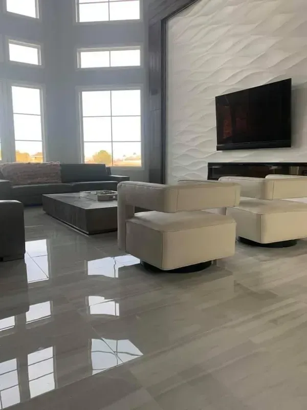 Modern living room with large windows, white chairs, dark sofa, wall-mounted TV, and glossy marble floor