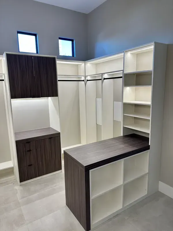 Walk-in closet with white built-in shelves, dark wood cabinets, and a center island under small windows