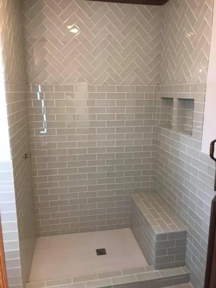 Tiled walk-in shower with bench, recessed shelf, and square floor drain